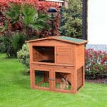 A wooden rabbit hutch on a grassy yard.