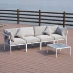 A white sofa set on a wooden deck with a view of the water.