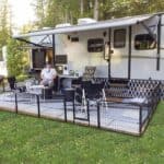 A man sits at a table in front of an rv.