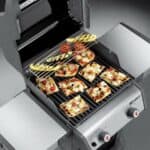 A gas grill with pizzas on it.