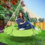 A woman reading a book on a green hammock.