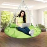 A woman using a laptop on a green hanging chair.