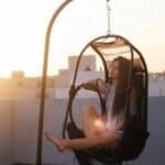 A woman sitting in a hammock on a rooftop.