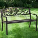 A black wrought iron bench in a garden.