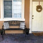 A bench in front of a house with a wreath on it.