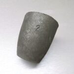 A cylindrical graphite crucible on a plain background.