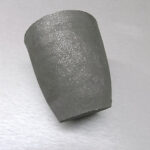 A cylindrical segment of a metallic substance displayed on a gray surface.