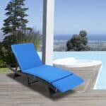 A blue lounge chair on a wooden deck next to a pool with a scenic view.