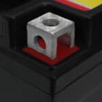 A close-up of a square metal nut secured on a red square inside a black compartment.