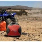 A generator and an atv in a dusty desert landscape.