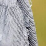 Close-up of water droplets on a textured white surface with a yellow background.