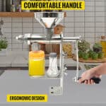 A metal manual juicer with an ergonomic handle on a kitchen counter, highlighting its comfortable design.