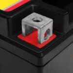 A metal clamp on a red square background, likely situated on a car battery terminal.