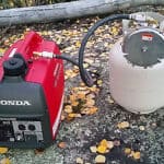 Portable honda generator connected to a propane tank outdoors.