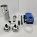 A collection of mechanical parts and tools, including a blue vacuum pump, cylinders, springs, and connectors.