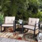 Two cushioned patio chairs with a matching side table set amidst lush greenery.