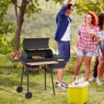 A group of friends enjoying an outdoor barbecue in a grassy area.