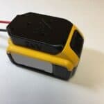 A compact yellow and black 24v power tool battery with red and black wires on a white background.