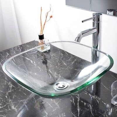 A bathroom sink with a glass top and marble counter top.