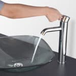 A person is pouring water into a glass sink.