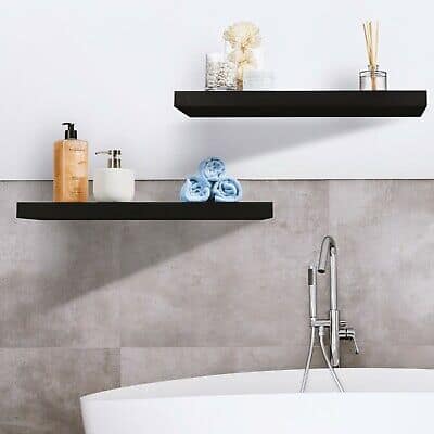 Two black floating shelves above a bathtub in a bathroom.