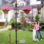 A bird feeder in a yard with a family in the background.