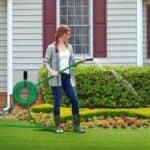 A woman is watering her lawn with a garden hose.