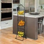 A kitchen with a three tier fruit rack.