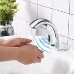 A person washing their hands in a bathroom sink.