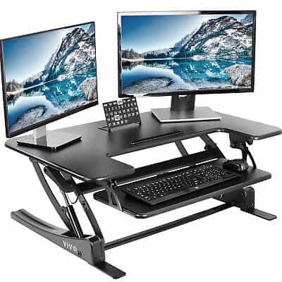 A standing desk with two monitors and a keyboard.