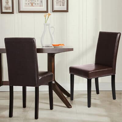 Two brown leather dining chairs in front of a wooden table.