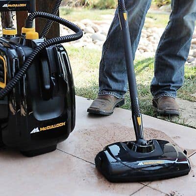 A man is using a vacuum cleaner on a patio.