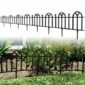 A black metal fence with a garden in the background.