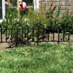 A black fence in front of a house with a pink flamingo.