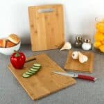 A wooden cutting board with vegetables and a knife.