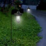 Two garden lanterns on a grassy path at night.