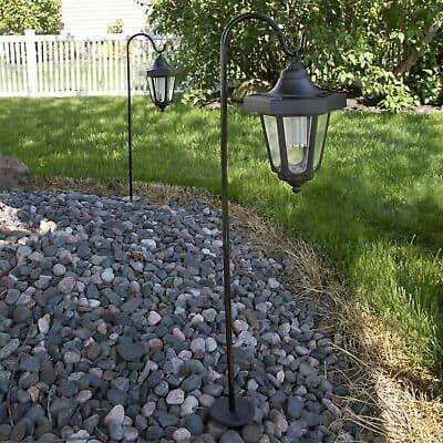 Two outdoor lanterns in a yard with rocks and gravel.