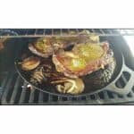 A cast iron skillet with steaks and onions on it.