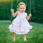 A baby girl swinging on a swing.