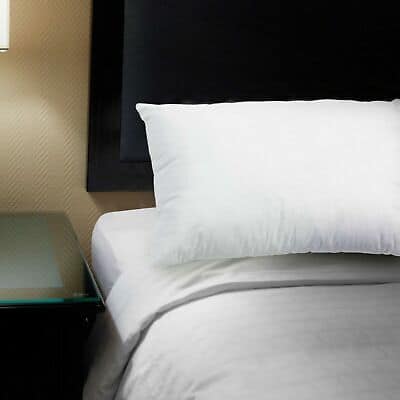 A white pillow on a bed in a hotel room.