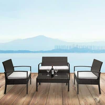 A black wicker patio furniture set on a wooden deck.