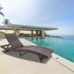 A rattan chaise lounge in front of a swimming pool.