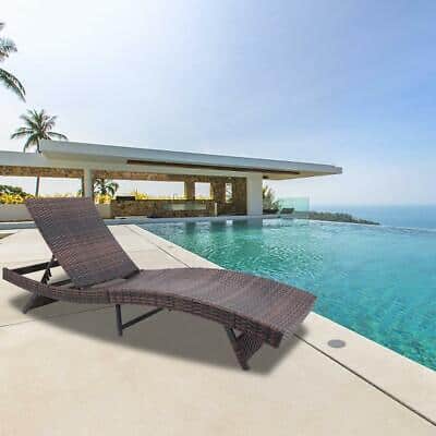 A rattan chaise lounge in front of a swimming pool.