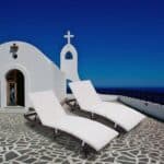 Two white chaise loungers in front of a church.