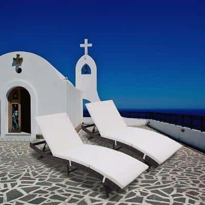 Two white chaise loungers in front of a church.