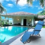 A blue lounge chair in front of a pool.