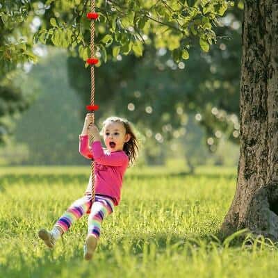 A little girl swinging on a tree swing.