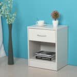 A white nightstand with books and a vase.