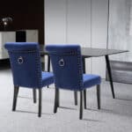 Two blue velvet dining chairs in a room with a table.