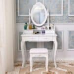 A white vanity table with a mirror and stool.